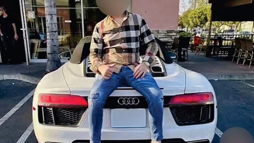 Suspect wearing designer shirt and jeans, sitting on Audi sports car in Los Angeles