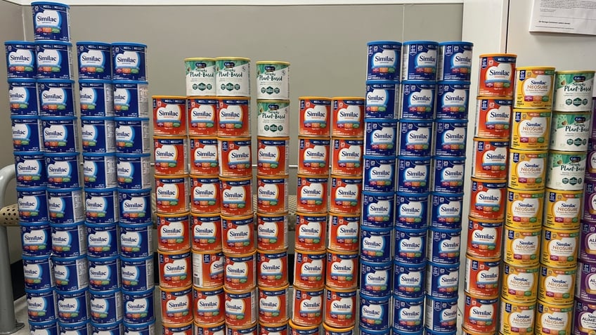 A wall of stolen baby formula cans stacked up in a row.