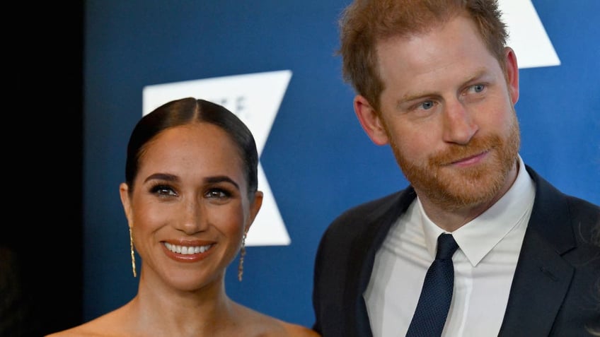 Meghan Markle and Prince Harry pose together for a photo at an event.