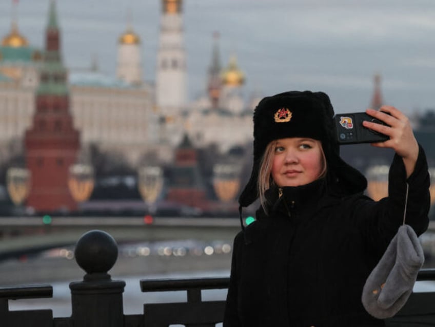 A woman takes a selfie picture with the Kremlin in distance on a frosty day in downtown Moscow on January 3, 2024, with the air temperature at around minus 24 degrees Celsius. (Photo by Vera Savina / AFP) (Photo by VERA SAVINA/AFP via Getty Images)