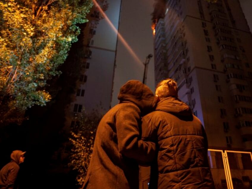 A couple comforts each other while watching a fire in a residential building after Russian