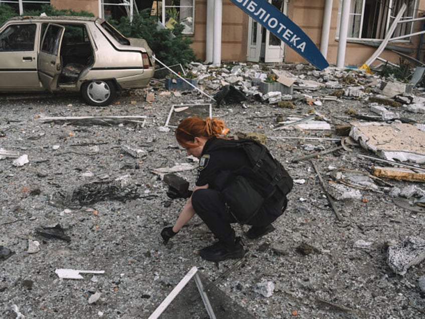 A police officer collects drone missile parts at the site of a Russian overnight attack in