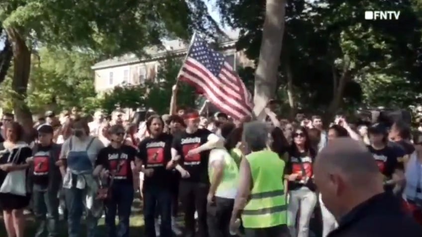 Patriotic students wave flag behind anti-Israel protesters