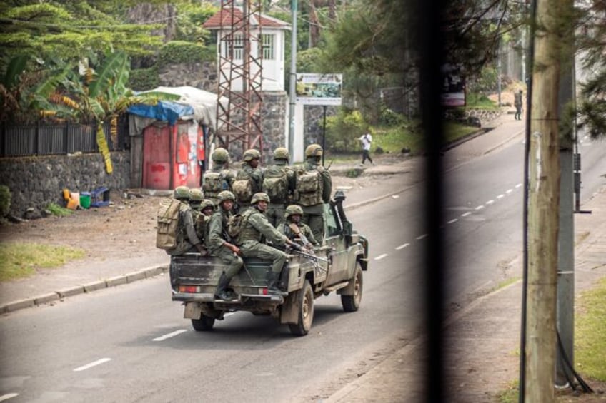 Armed men travel in a pickup truck, devoid of any insignia or markings, as they drive thro