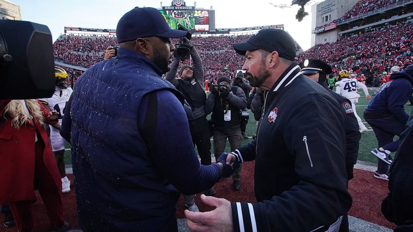 Sherrone Moore shakes hands with Ryan Day