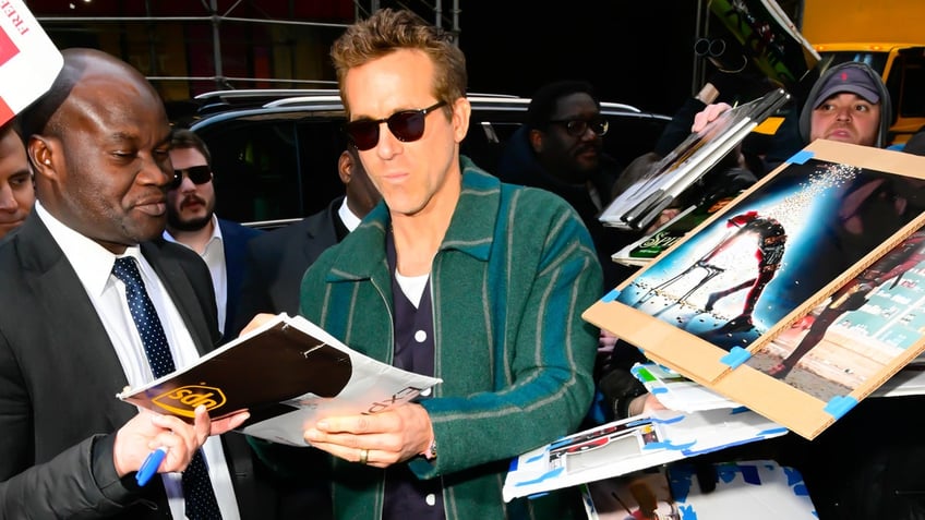 Ryan Reynolds wears green striped jacket and sunglasses to sign autographs in New York City