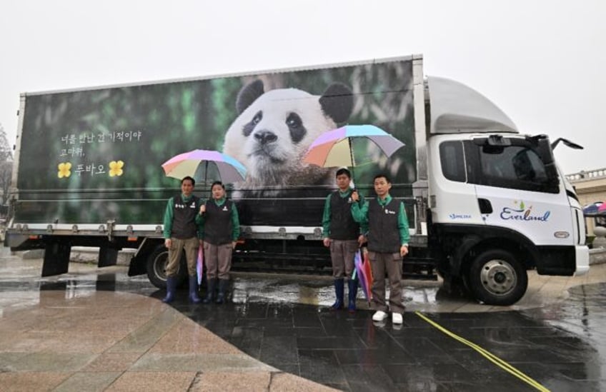 Zookeepers pose for photos in front of a vibration-free special vehicle carrying giant pan