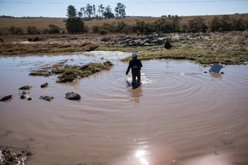 An emergency worker searches for bodies in a pond after deadly floods in South Africa's Ea