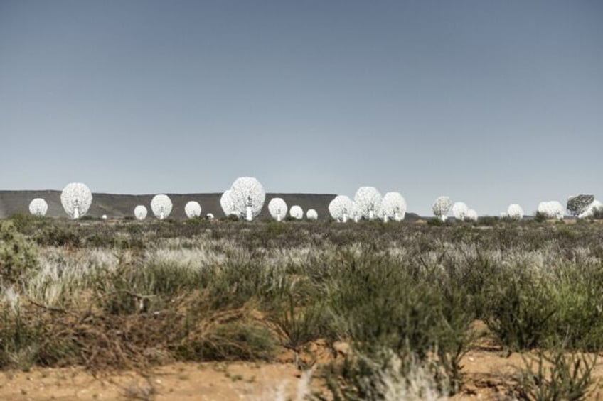 The MeerKAT radio telescope is made up of 64 giant white dishes that stand in a semi-deser