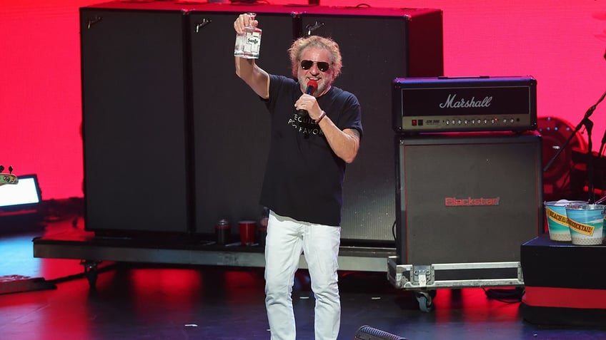 Sammy Hagar holding a bottle of Santo Spirits tequila on stage