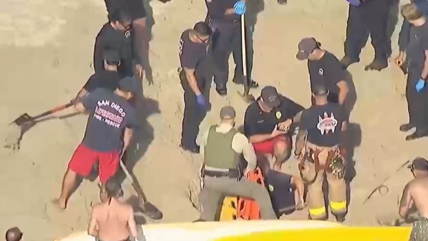 rescuers digging out teen at beach