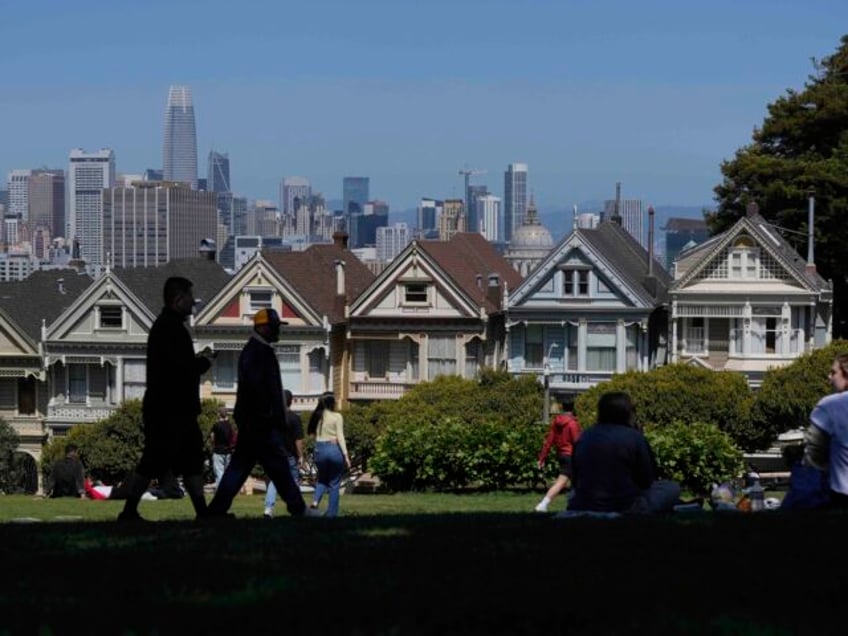 People walk along at path in front of the "Painted Ladies," a row of historical