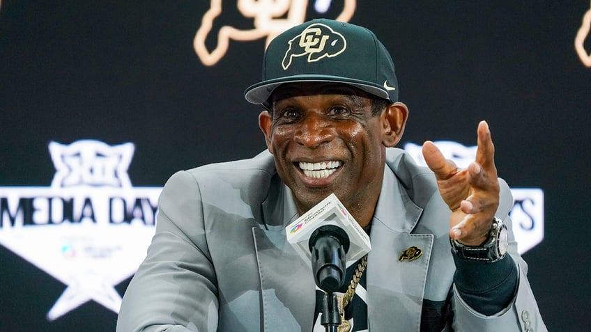Deion Sanders smiles at microphone