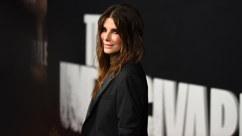 Sandra Bullock looks slightly over her shoulder in a black outfit on the carpet