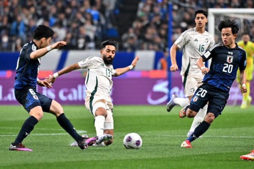 Saudi Arabia's defender Nawaf Bu Washl (C) competes for the ball with Japan's midfielders
