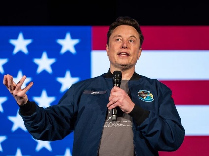 Elon Musk speaks in front of a flag (1)