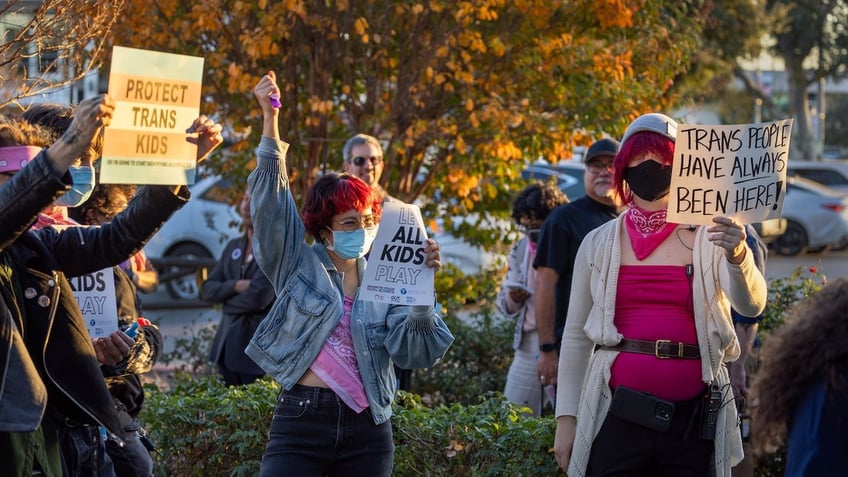 Transgender athlete supporters hold up signs as an overflow crowd converges outside the Riverside Unified School District meeting Thursday night to debate the rights of transgender athletes to compete in high school sports, Thursday, Dec. 19, 2024. 