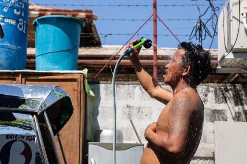 A man showers with a hose during hot weather in Manila on April 28, 2024