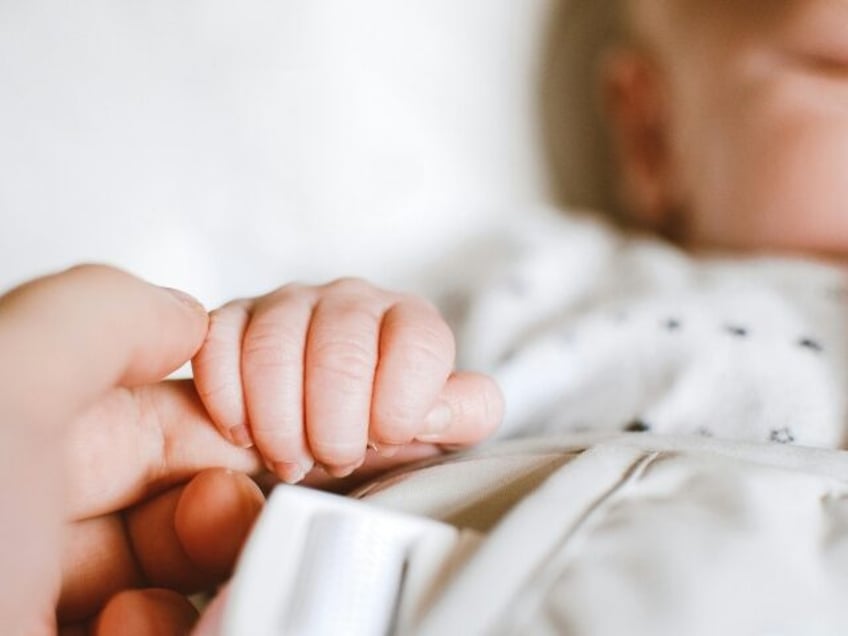 newborn baby grasps a finger