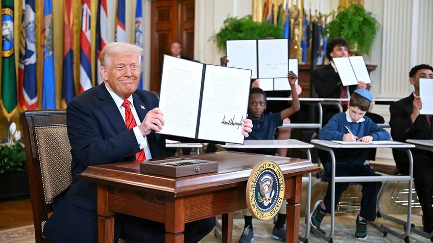 President Donald Trump holds an executive order on the Department of Education after signing it in the East Room of the White House in Washington on March 20, 2025