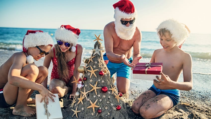 Family opening gift under sand Christmas tree.