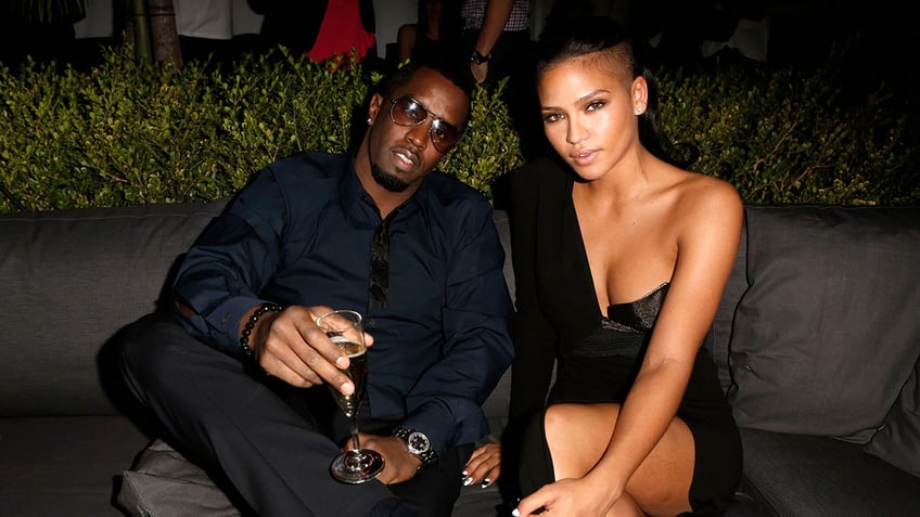 Diddy and Cassie sit on a couch