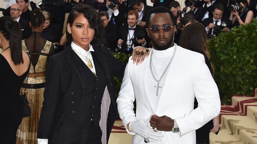 Cassie wearing a black suit and Sean "Diddy" Combs in a white suit