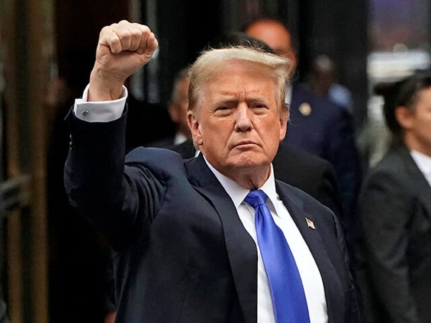 Former US President and Republican presidential candidate Donald Trump holds up a fist as