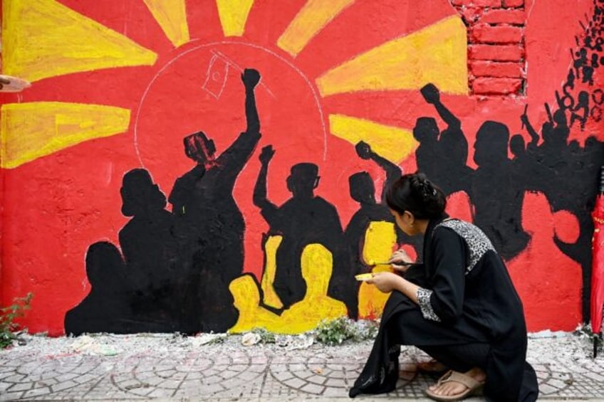 A college student paints graffiti on a wall at Dhaka university after the student-led prot