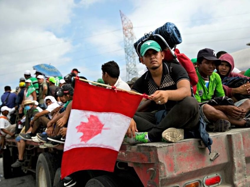 Honduran migrant Fernando Najar Guillen, 22, carries a handmade Canadian flag as he rides