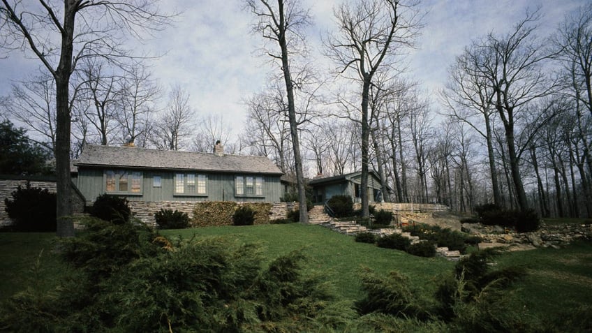 Ellsworth Bunker vsiible on landscaped hilltop at Camp David