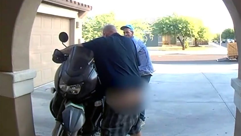 Two thieves attempting to steal a motorcycle, one with his pants falling down