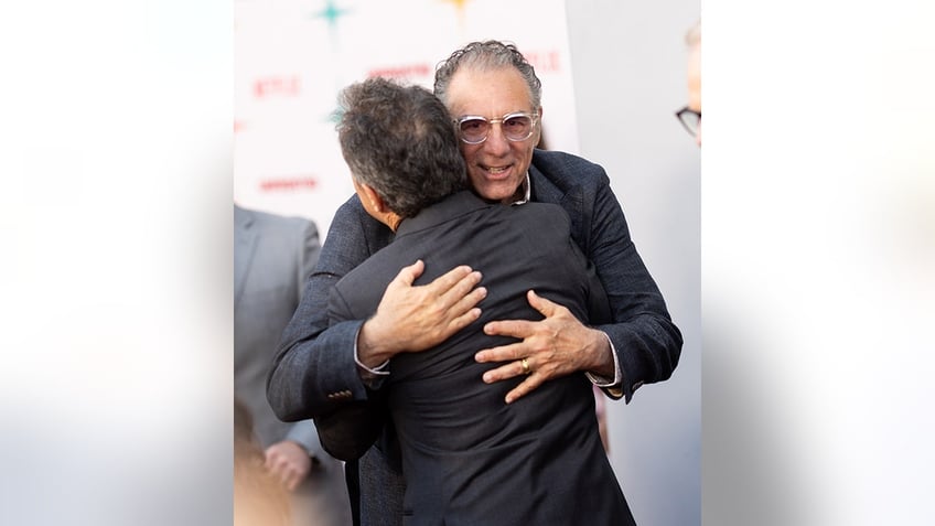 Michael Richards hugs Jerry Seinfeld on the carpet