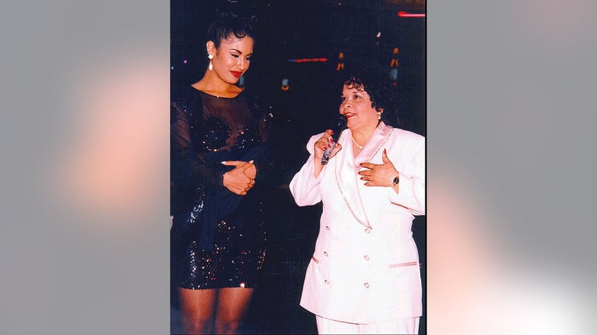 Selena looking at Yolanda Saldivar, who is holding a mic