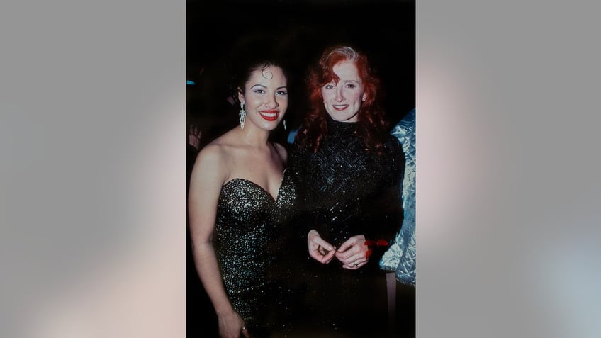 Selena posing next to Bonnie Raitt as they both wear black