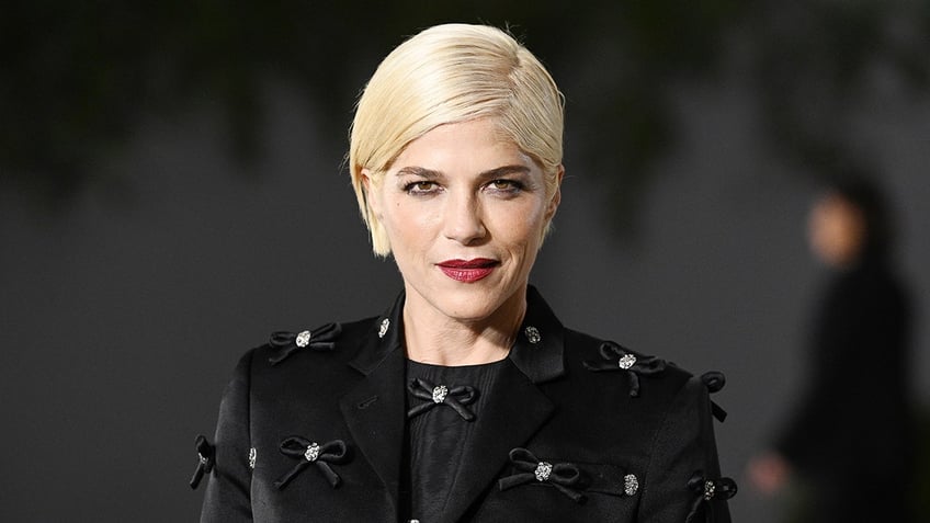 Selma Blair in a black blazer with bows stares directly into the camera