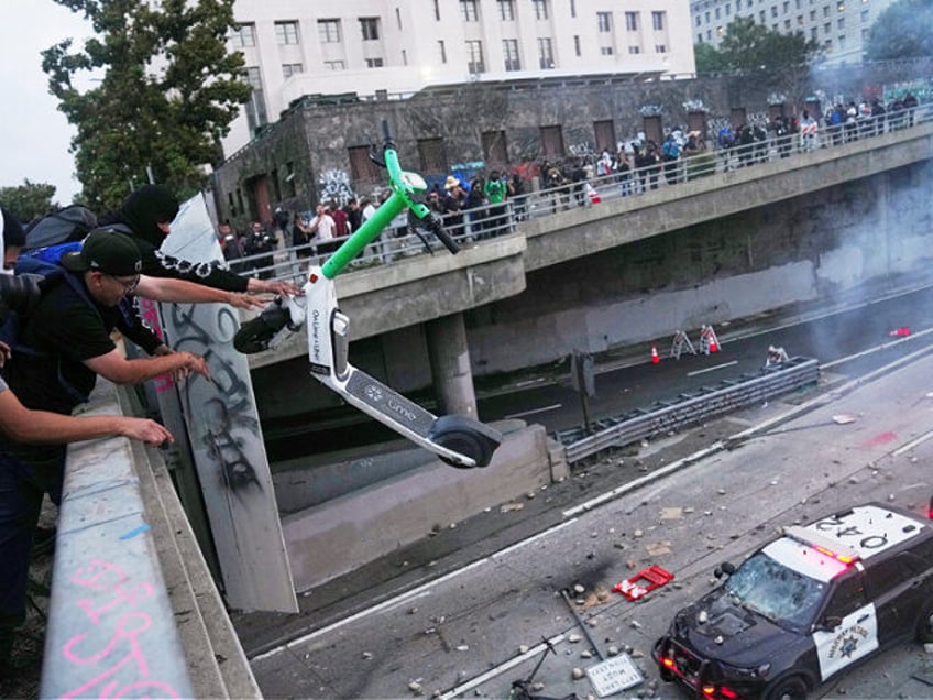 A protester throws a scooter at a police vehical near the metropolitan detention center of