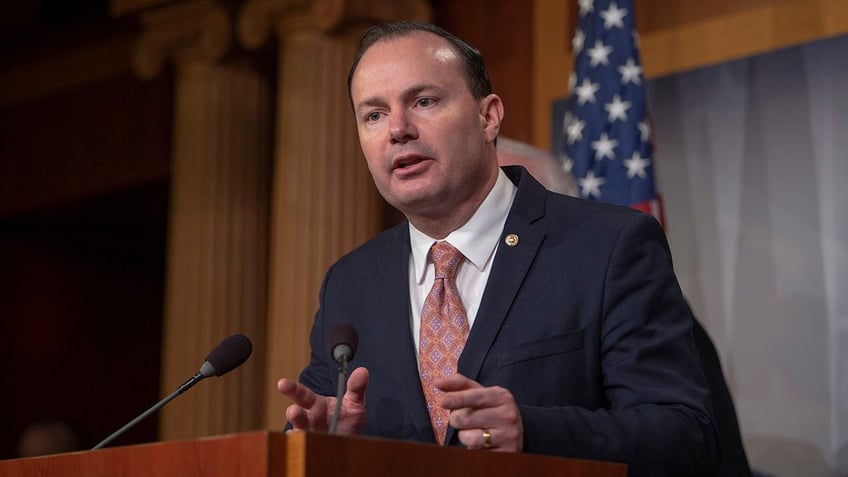 Sen. Mike Lee speaks at podium with American flag in background