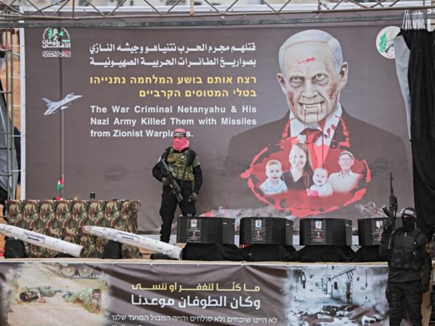 Armed Palestinian militants stand next to the coffins on stage before handing over the bod