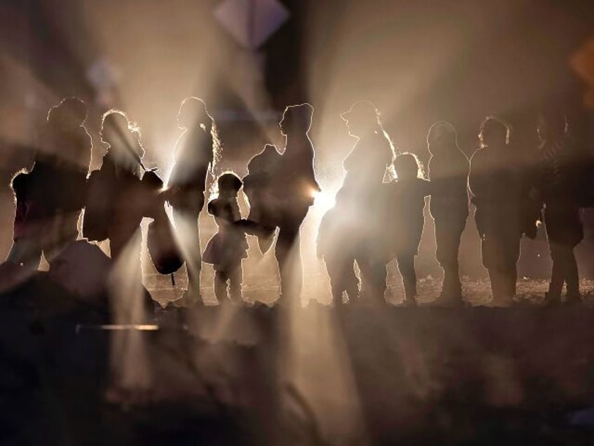 LUKEVILLE, ARIZONA - DECEMBER 05: Immigrant families wait to be processed by U.S. border authorities after crossing the U.S.-Mexico border on December 05, 2023 in Lukeville, Arizona. A surge of immigrants illegally passing through openings cut by smugglers in the border wall has overwhelmed U.S. immigration officials, causing them to …