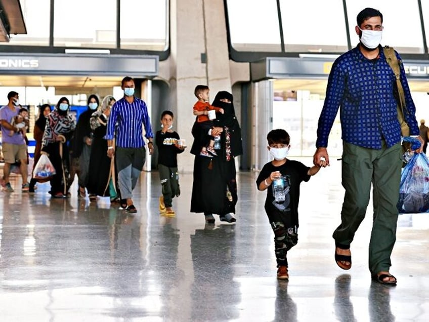 DULLES, VIRGINIA - AUGUST 27: Refugees arrive at Dulles International Airport after being evacuated from Kabul following the Taliban takeover of Afghanistan August 27, 2021 in Dulles, Virginia. Refugees continued to arrive in the United States one day after twin suicide bombings at the gates of the airport in Kabul …