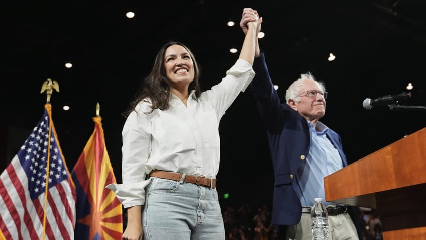 Sen. Bernie Sanders, I-Vt., and Rep. Alexandria Ocasio-Cortez, D-N.Y., greet the crowd together during a "Fighting Oligarchy" tour event at Arizona State University, Thursday, March 20, 2025, in Tempe, Ariz. (AP Photo/Ross D. Franklin)