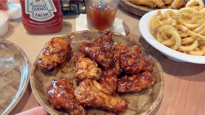 Hooters wings and curly fries are shown on a table.