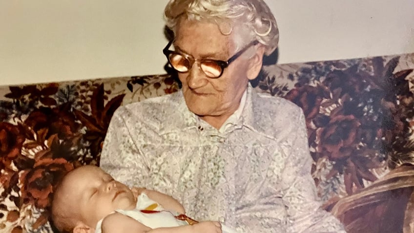 An elderly woman holding a baby.