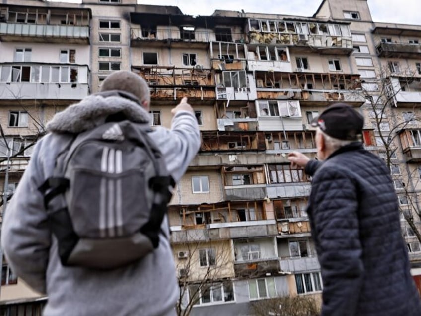 KYIV, UKRAINE - MARCH 23: Men stand and look at a damaged high-rise apartment building aft