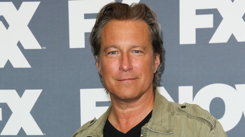 John Corbett smiling and wearing a khaki jacket