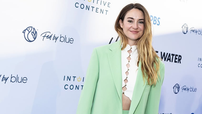 Shailene Woodley in a white cropped shirt and mint green blazer soft smiles on the carpet