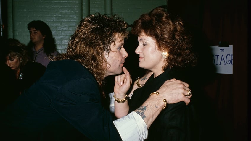 Ozzy Osbourne staring at his wife Sharon as she touches his face