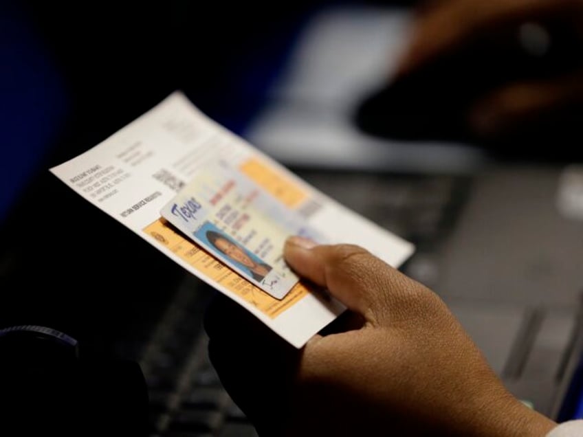 FILE - In this Feb. 26, 2014 file photo, an election official checks a voter's photo