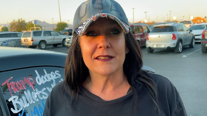 Woman wearing hat that says "USA" standing in parking lot